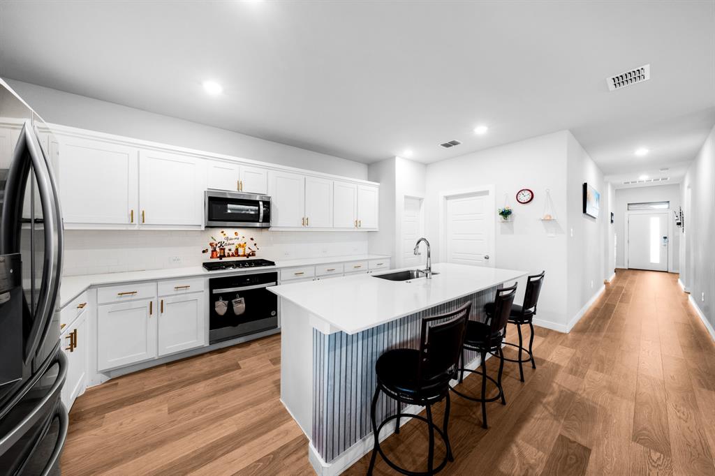 1012 Breezy Street Princeton, TX 75407 - Photo 4 of 34 a kitchen with a sink a stove a refrigerator and chairs