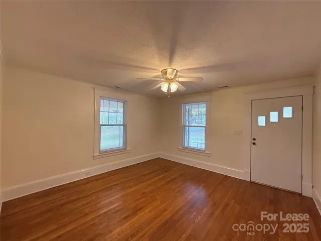 a view of empty room with wooden floor and fan