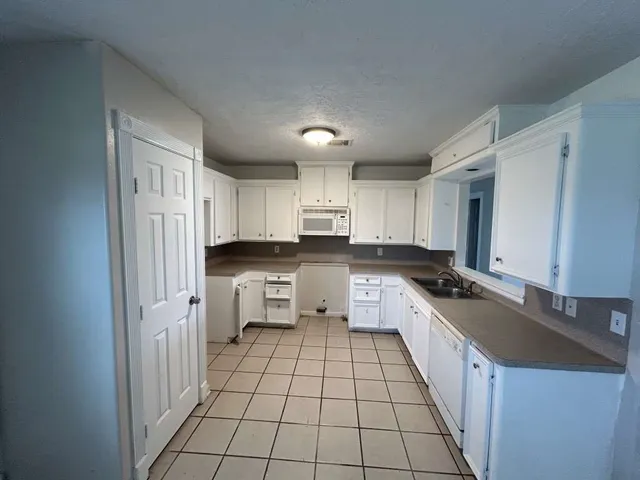 a large white kitchen with a stove a sink dishwasher and a refrigerator