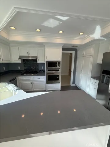 a living room with stainless steel appliances kitchen island granite countertop a refrigerator and a stove top oven