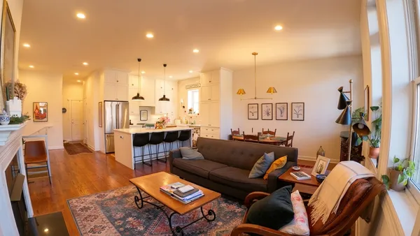 a living room with furniture kitchen view and a chandelier