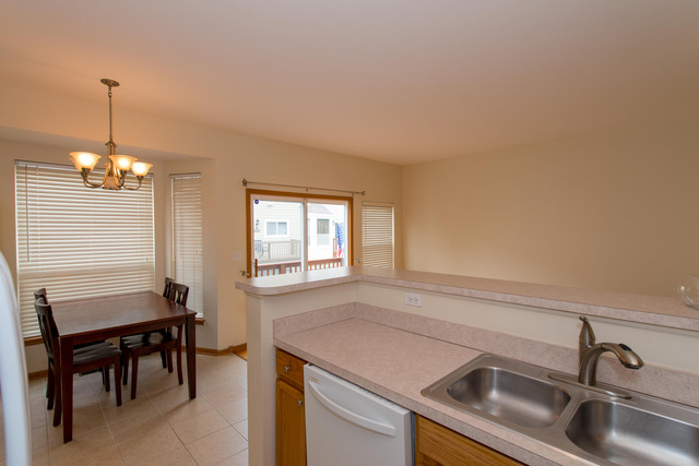 2422 Courtyard Circle, Unit 3 Aurora, IL 60506 - Photo 11 of 25 a kitchen that has a sink a table and chairs in it