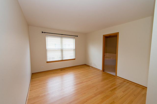 2422 Courtyard Circle, Unit 3 Aurora, IL 60506 - Photo 20 of 25 a view of an empty room with wooden floor and a window
