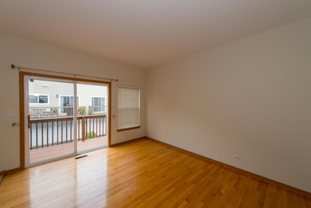 2422 Courtyard Circle, Unit 3 Aurora, IL 60506 - Photo 6 of 25 a view of an empty room with wooden floor and a window