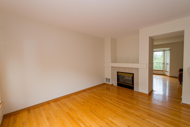 2422 Courtyard Circle, Unit 3 Aurora, IL 60506 - Photo 7 of 25 a view of empty room with wooden floor and fireplace