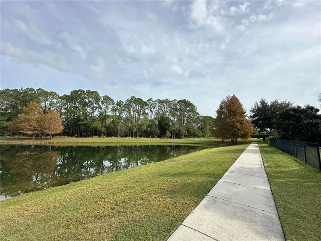 a view of a lake with a yard and large trees