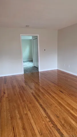a view of an empty room with wooden floor and closet