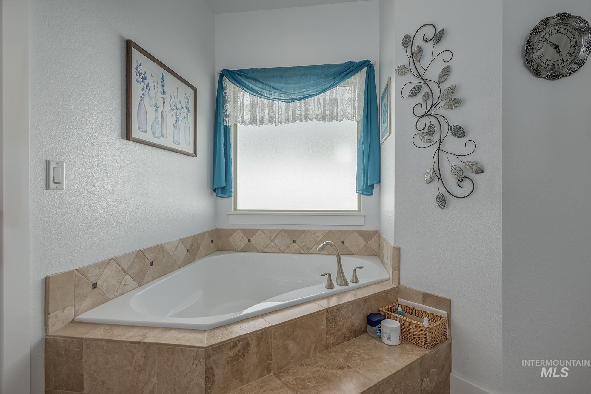 420 West Indianhead Road Weiser, ID 83672 - Photo 26 of 40 Corner soaking tub with brushed nickel fixtures, surrounded by neutral-toned tile and a tiled step
