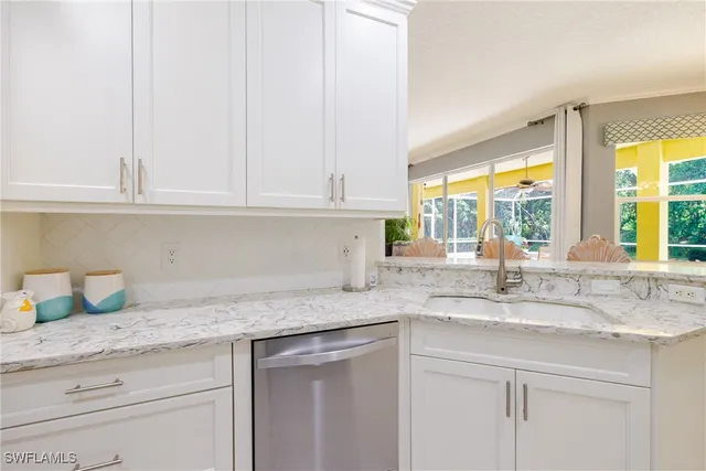 a kitchen with granite countertop stainless steel appliances white cabinets and a window