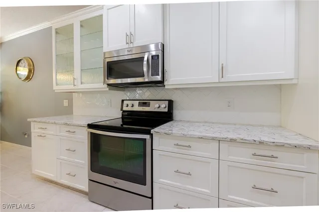 a kitchen with white cabinets and black appliances