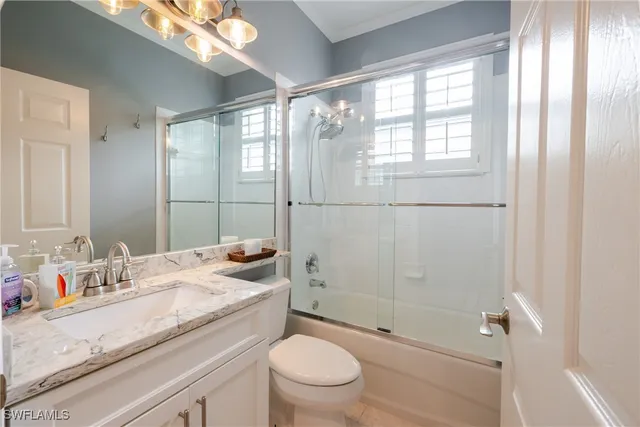 a bathroom with a granite countertop sink a mirror a toilet and shower