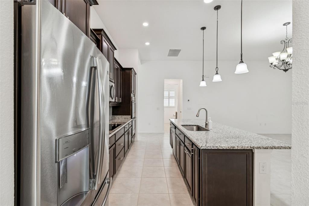 711 San Joaquin Road Kissimmee, FL 34759 - Photo 9 of 41 a kitchen with stainless steel appliances granite countertop a sink a refrigerator and a wooden floor
