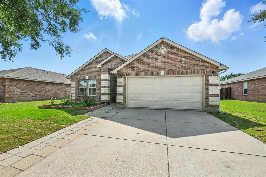 Traditional-style home featuring brick siding, concrete driveway, a front lawn, and a garage