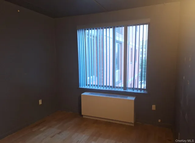 an empty room with wooden floor and a window