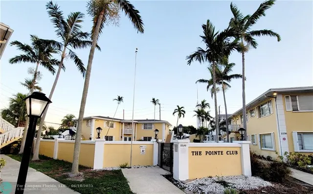 a front view of a house with a garden and palm trees