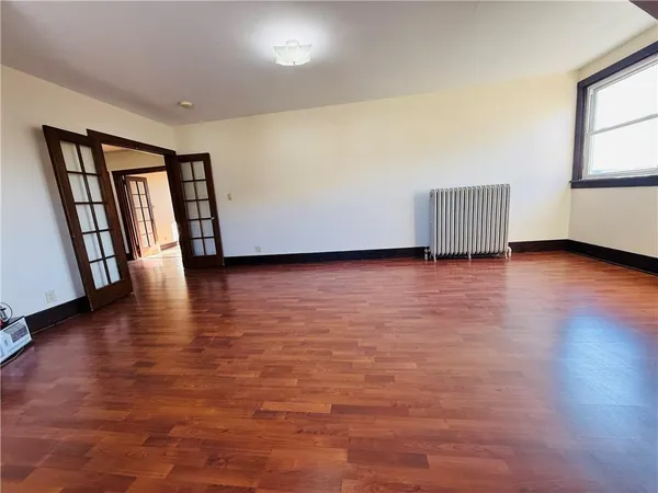 a view of an empty room with wooden floor and windows