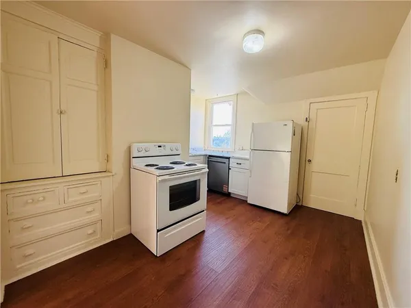 a kitchen with a white stove and wooden floors