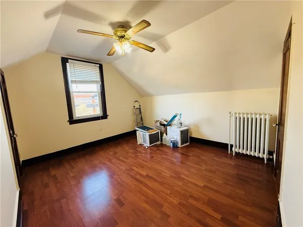 an empty room with wooden floor and fan