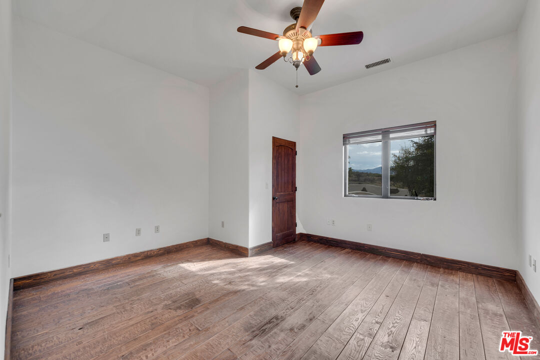 32140 Windrush Road Agua Dulce, CA 91390 - Photo 25 of 41 an empty room with wooden floor chandelier fan and windows
