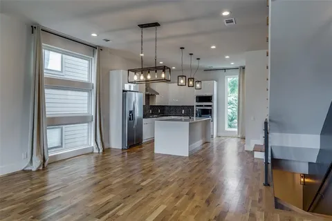 an open kitchen with a refrigerator and wooden floor