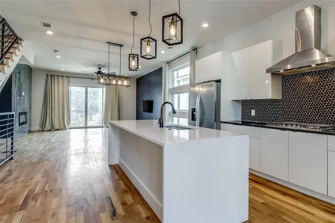 a large kitchen with stainless steel appliances a large center island attached withe living room