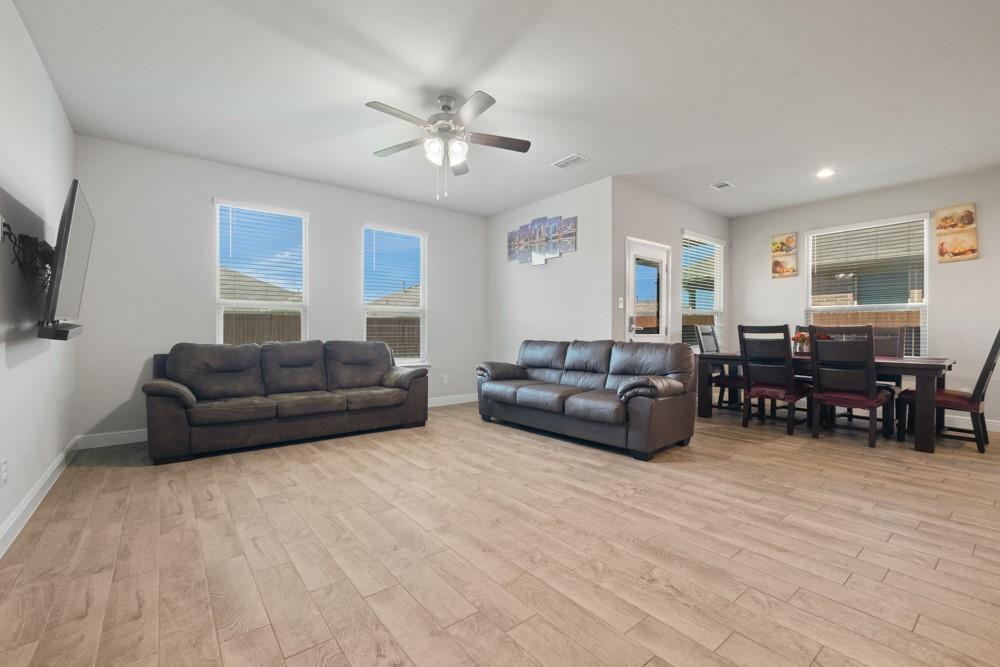 1112 Croxley Way Justin, TX 76247 - Photo 5 of 18 Open-concept living area featuring wood-look tile flooring, light gray walls, and multiple windows with blinds