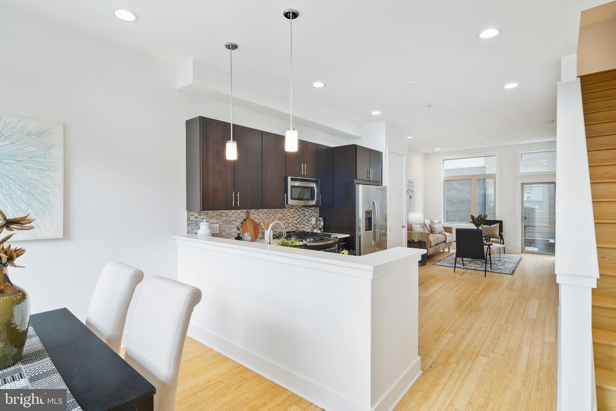 1135 Hope Street, Unit 18 Philadelphia, PA 19123 - Photo 3 of 21 a kitchen with stainless steel appliances kitchen island granite countertop a refrigerator a stove a sink dishwasher with a dining table and chairs