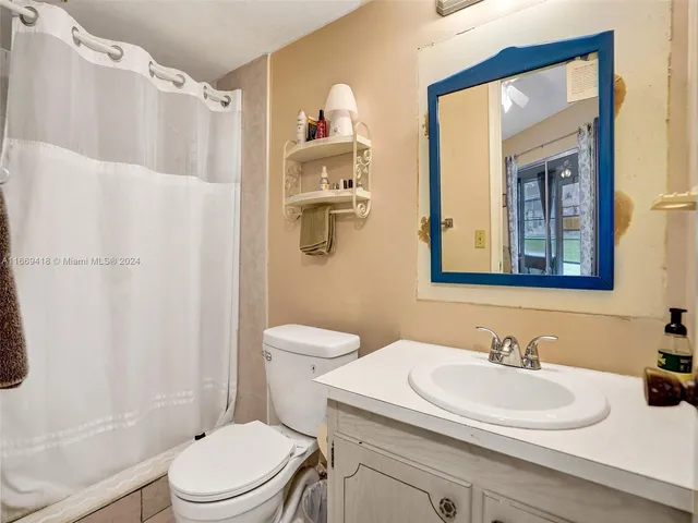 a bathroom with a sink a toilet and shower curtain
