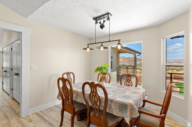 2591 East Washington Dam Road Washington, UT 84780 - Photo 14 of 67 Dining area featuring a contemporary linear pendant light fixture, light wood-finish flooring, and multiple windows offering expansive territorial scenery