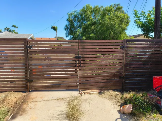a view of a street with flowers and wooden fence