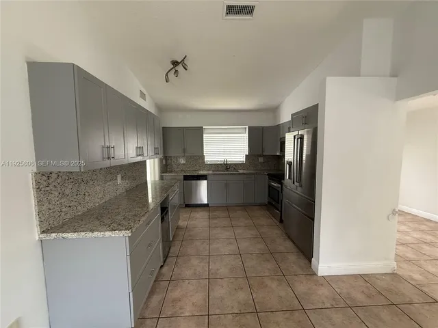 a kitchen with stainless steel appliances granite countertop a refrigerator and a sink
