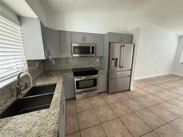 a kitchen with granite countertop a sink a stove and refrigerator