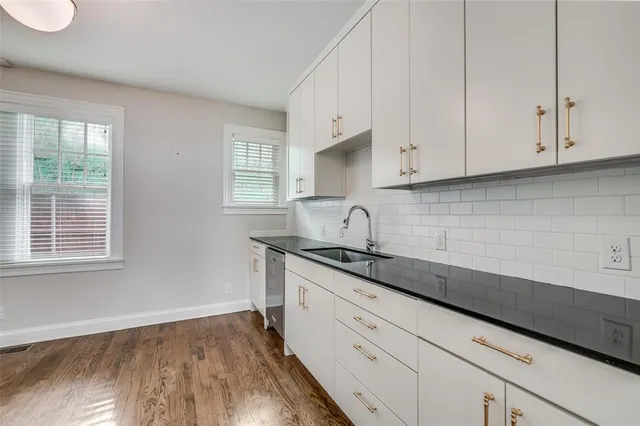 a kitchen with granite countertop white cabinets and a sink