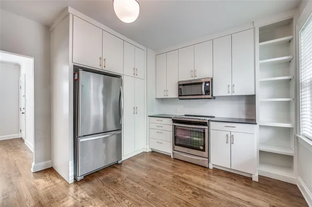 a kitchen with granite countertop white cabinets and stainless steel appliances
