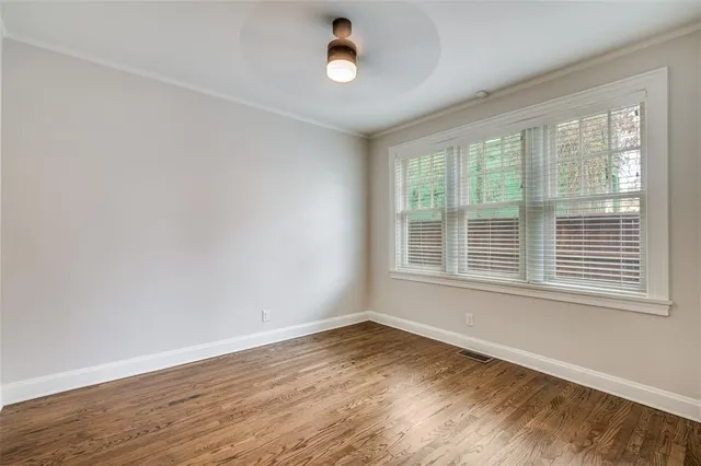 a view of an empty room with wooden floor and a window