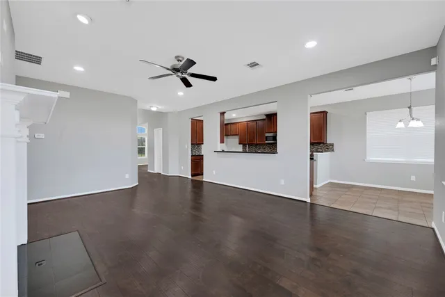 a view of empty room with wooden floor and ceiling fan