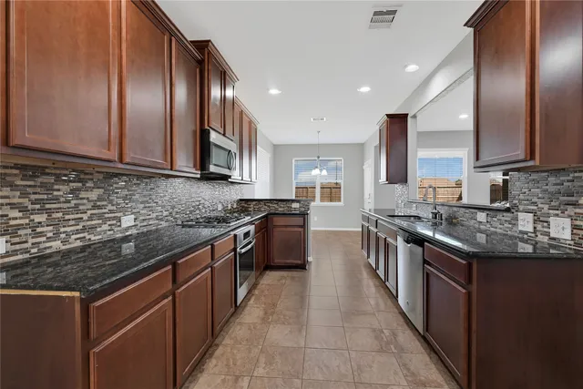 a large kitchen with stainless steel appliances granite countertop a stove top oven a sink and dishwasher