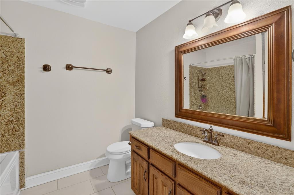 2010 Libby Lane Grand Prairie, TX 75050 - Photo 14 of 24 a bathroom with a granite countertop sink a toilet and a mirror