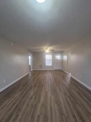 a view of empty room with window and wooden floor