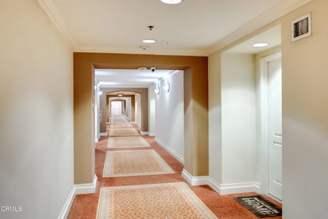 a view of a hallway with wooden floor and a bathroom