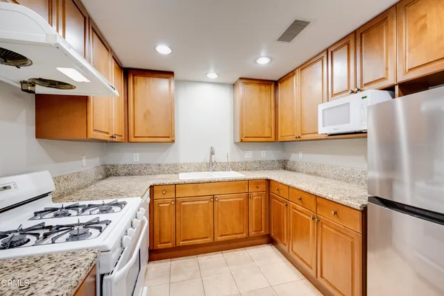 a kitchen with stainless steel appliances granite countertop a sink stove and refrigerator