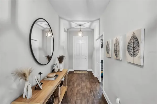 a kitchen with stainless steel appliances kitchen island granite countertop a refrigerator a sink dishwasher and white cabinets with wooden floor