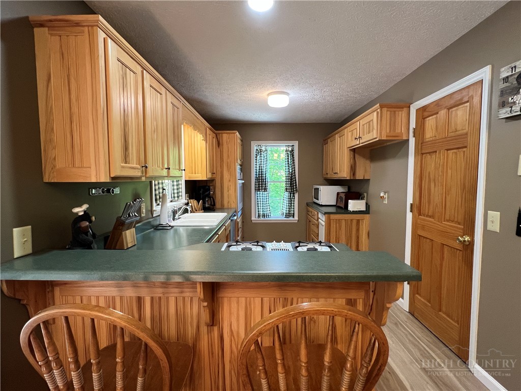139 New River Ridge Estates Laurel Springs, NC 28644 - Photo 10 of 34 a kitchen with stainless steel appliances granite countertop a refrigerator a stove and a sink with wooden floor