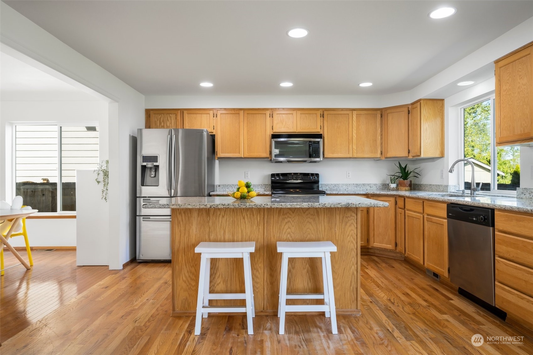 4318 Northeast 2nd Court Renton, WA 98059 - Photo 5 of 29 a kitchen with stainless steel appliances granite countertop a stove a sink a microwave a refrigerator with a dining table and chairs