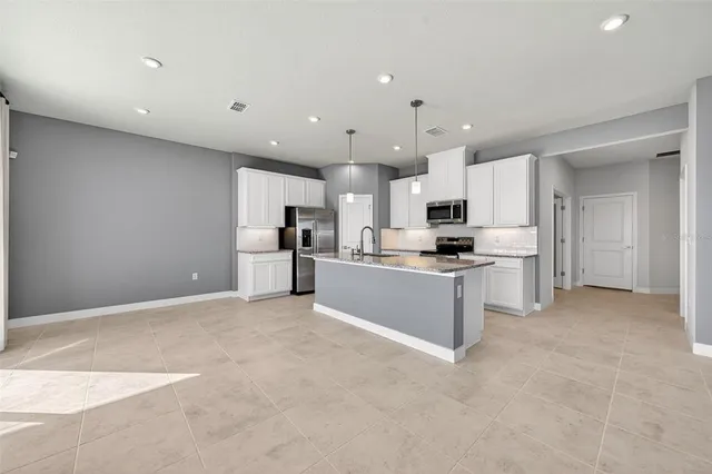 a large kitchen with stainless steel appliances kitchen island granite countertop a stove a sink a microwave and a refrigerator