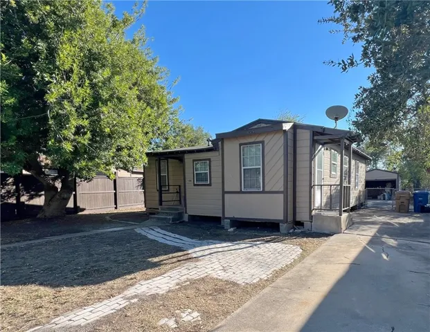 a front view of a house with a garden and tree