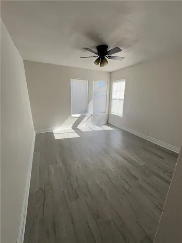 a view of empty room with wooden floor and fan