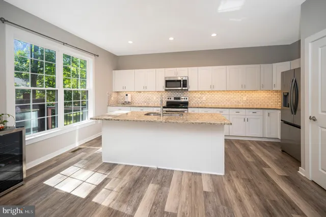 a kitchen with stainless steel appliances granite countertop a sink a stove a refrigerator and cabinets