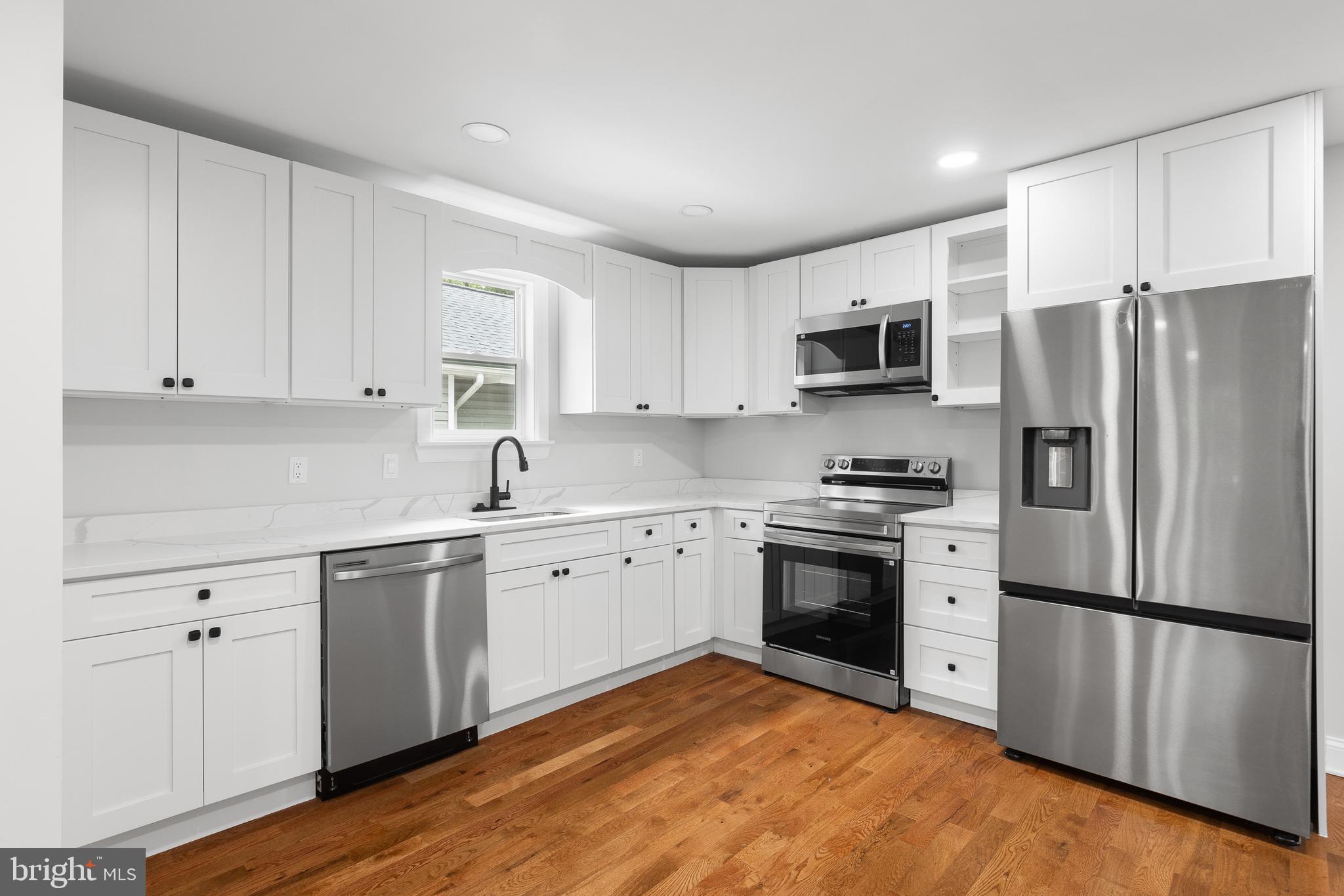 1528 Hunt Avenue Landover, MD 20785 - Photo 2 of 27 a kitchen with stainless steel appliances granite countertop a stove top oven a refrigerator and white cabinets with wooden floor