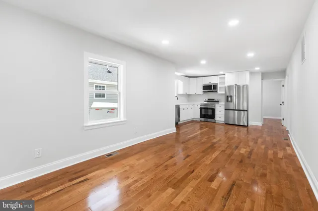 a view of empty room with kitchen and window
